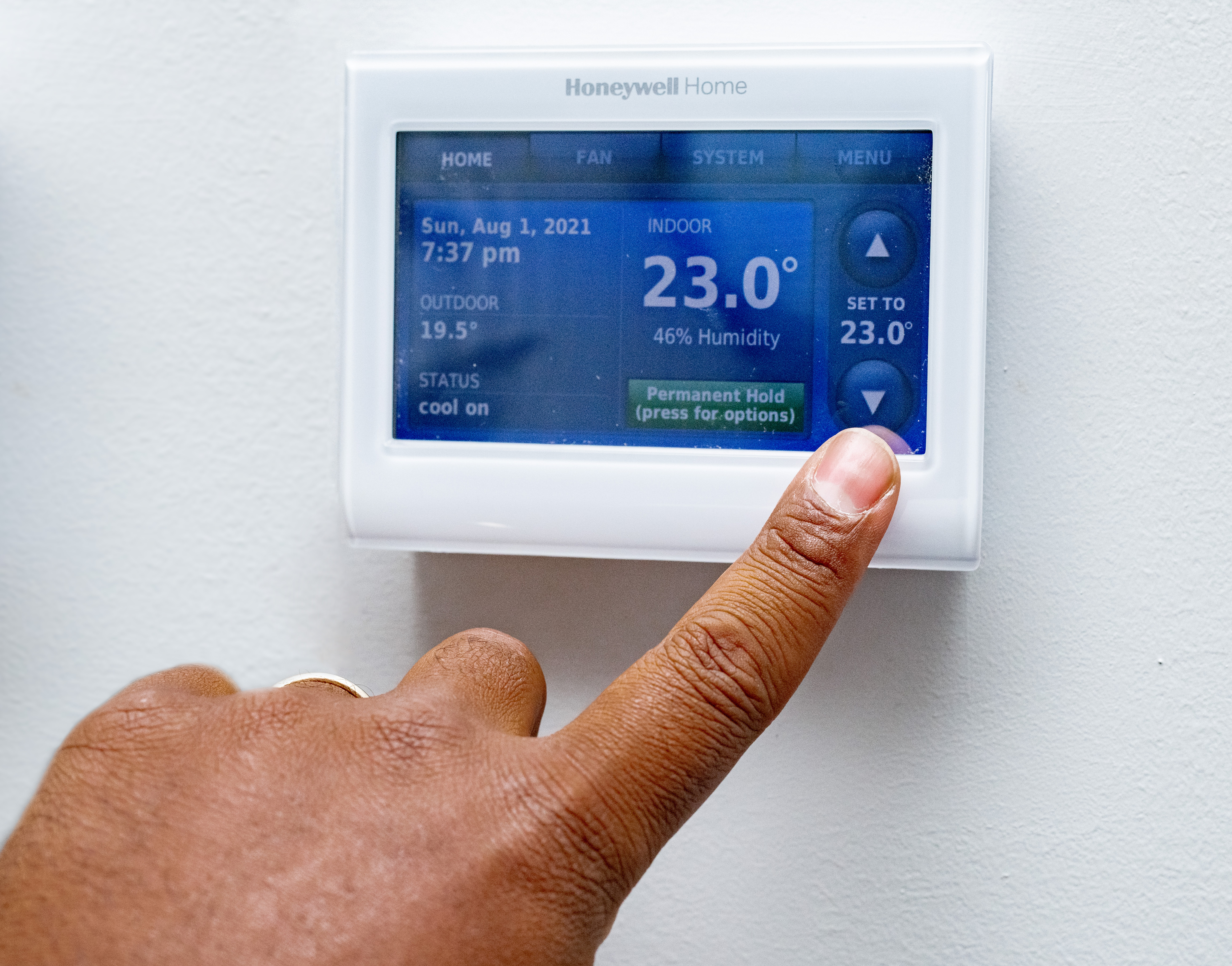 hand adjusting a digital thermostat