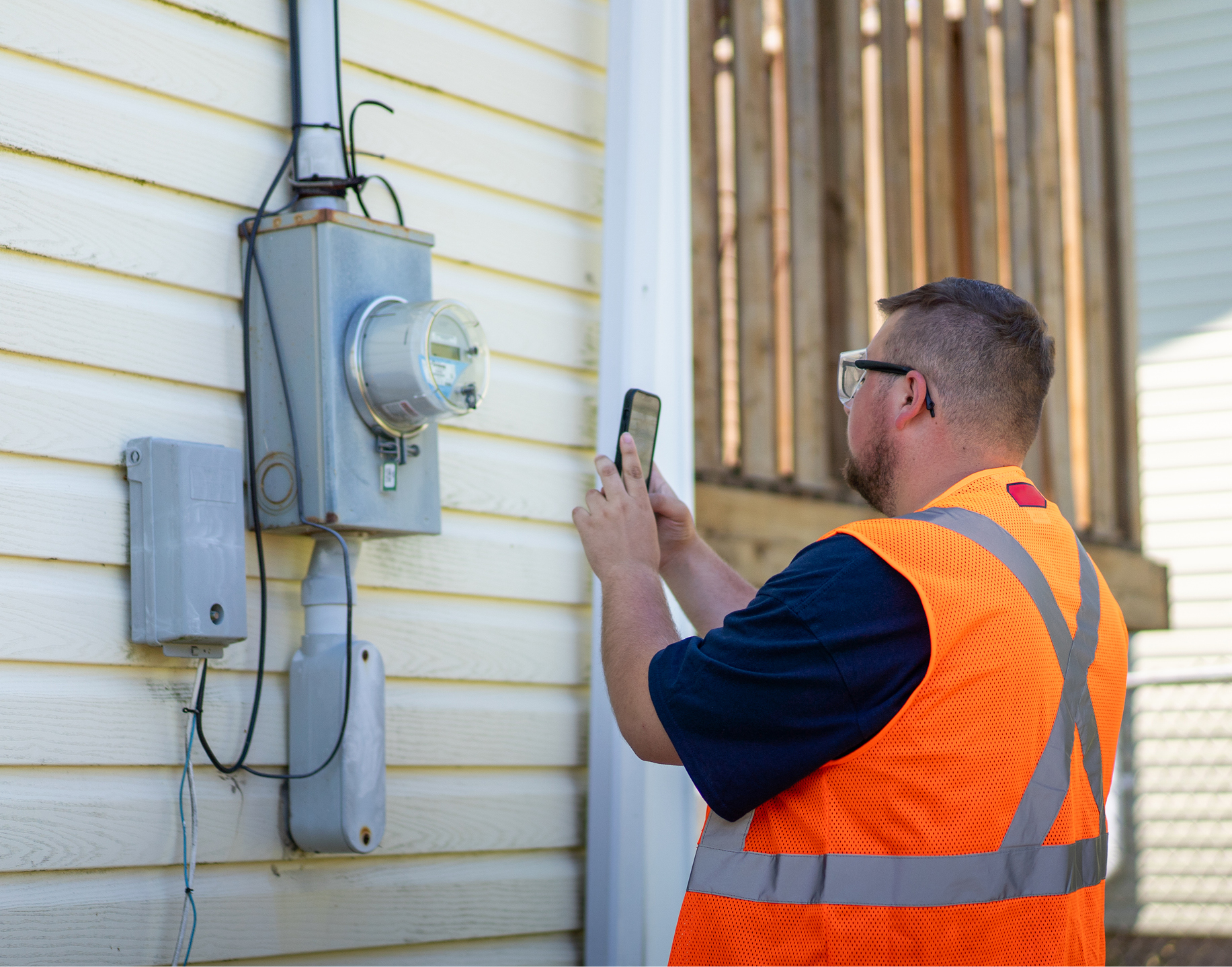 A meter reader looking at a power meter on a home