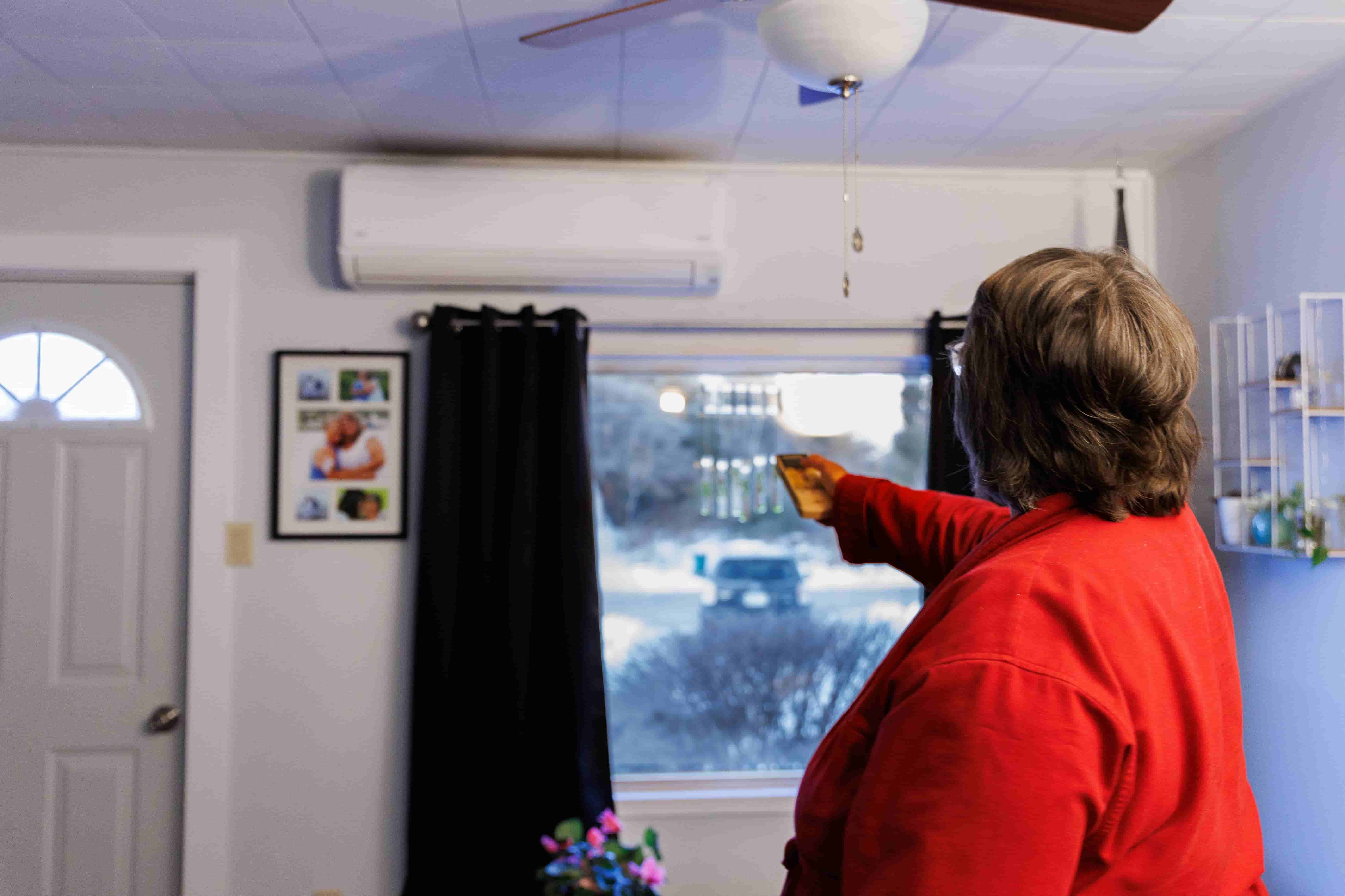 A man wearing a red jacket with a heater remote in her hand
