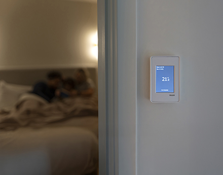 A home with a family having a thermostat showing 22 degrees